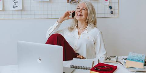 Rentnerin in einem Büro lächelnd am telefonieren, Beitragsbild zum Thema Hinzuverdienst in der Rente