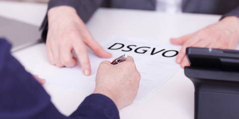 Eine Person reicht einer anderen Person ein DSGVO-Formular zum Unterschreiben