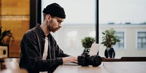 Junger Mann mit Beanie im Büro an einem Laptop Artikelbild von Lexware