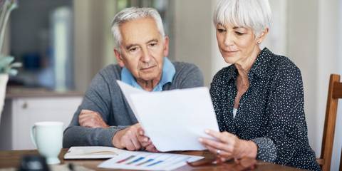 Zwei ältere Menschen sitzen an einem Tisch und sehen ihre Finanzen durch