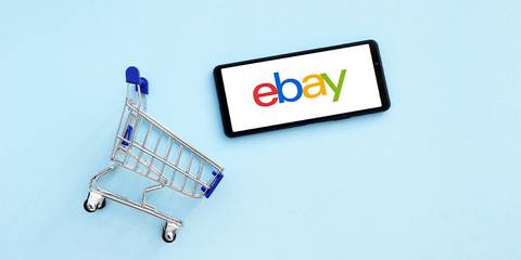 eBay Logo auf Smartphone und kleiner Einkaufswagen