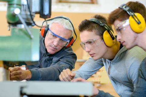 Drei Männer mit Ohrschutz arbeiten in einer Werkstatt