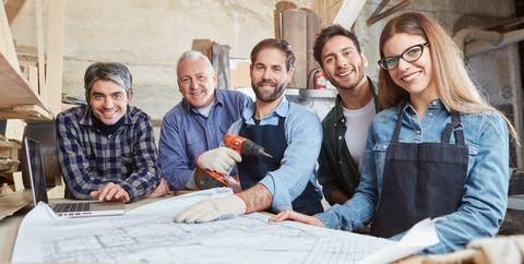 Vier Männer und eine Frau vor einem Bauplan in einer Werkstatt