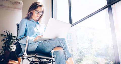 Frau sitzt auf einem Stuhl und arbeitet am Laptop