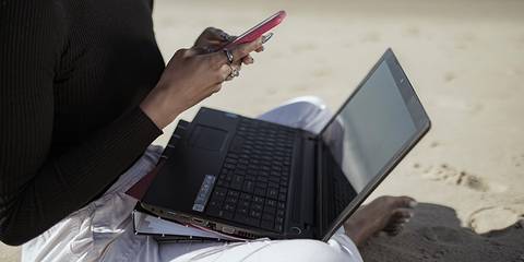 Frau arbeitet am Strand mit Laptop 