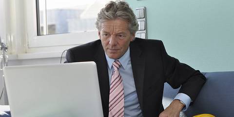 Mann im Anzug vor einem Laptop
