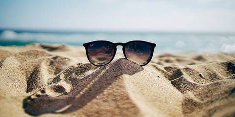 Sonnenbrille auf einem Sandstrand vor dem Meer