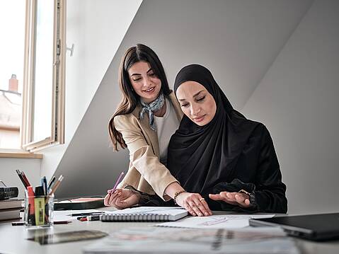 Bild von Lexware: Zwei Frauen am Schreibtisch, die zusammen in Unterlagen schauen