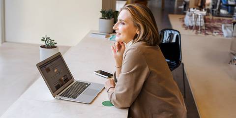 Frau in einem offenem Büro vor einem Laptop