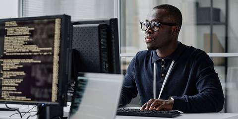 Junger Entwickler mit Brille, der sich auf seine Arbeit am Computer konzentriert