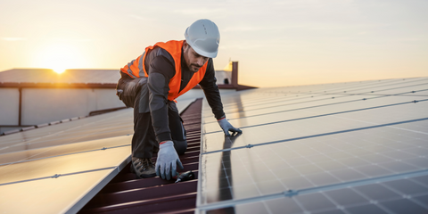 Ein Handwerker auf Solarpanelen auf einem Dach