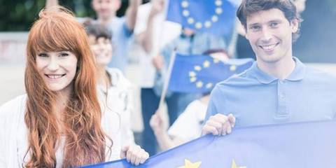 Eine Gruppe von Menschen tragen fröhlich eine Fahne mit Europaflagge 