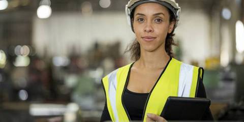 Porträt einer Fabrikarbeiterin mit digitalem Tablet in einer Werkstatt