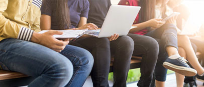 vier Personen die ihren Laptop oder ihr Notizbuch auf dem Schoß haben, die Köpfe sind abgeschnitten