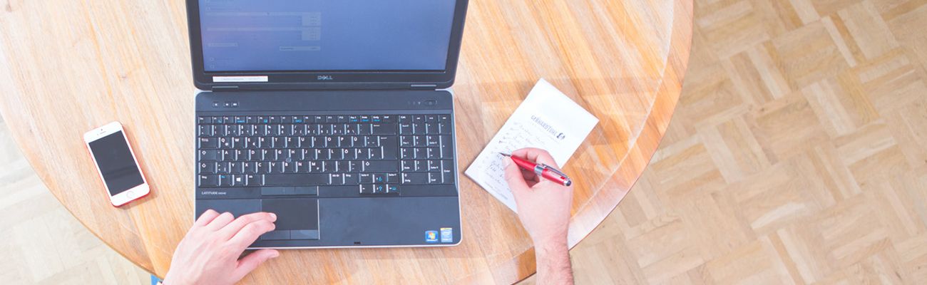 Person an einem Schreibtisch mit Laptop und Smartphone