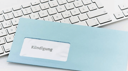 blauer Briefumschlag mit der Aufschrift "Kündigung" im Brieffenster liegt schräg auf Tastatur.